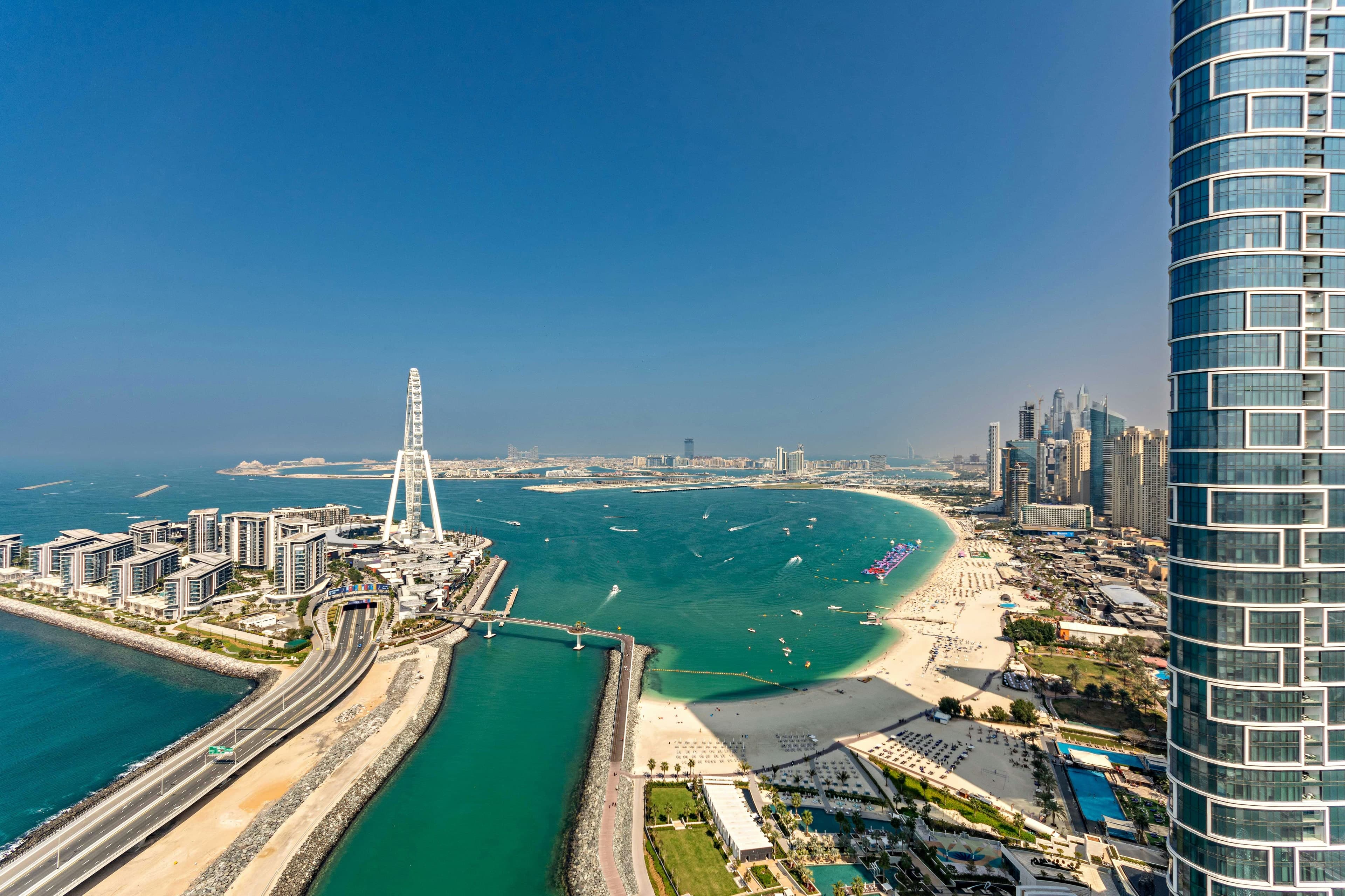 Bluewaters Island and its road bridge beside the curving beach of JBR, with the towers of Dubai Marina in the distance