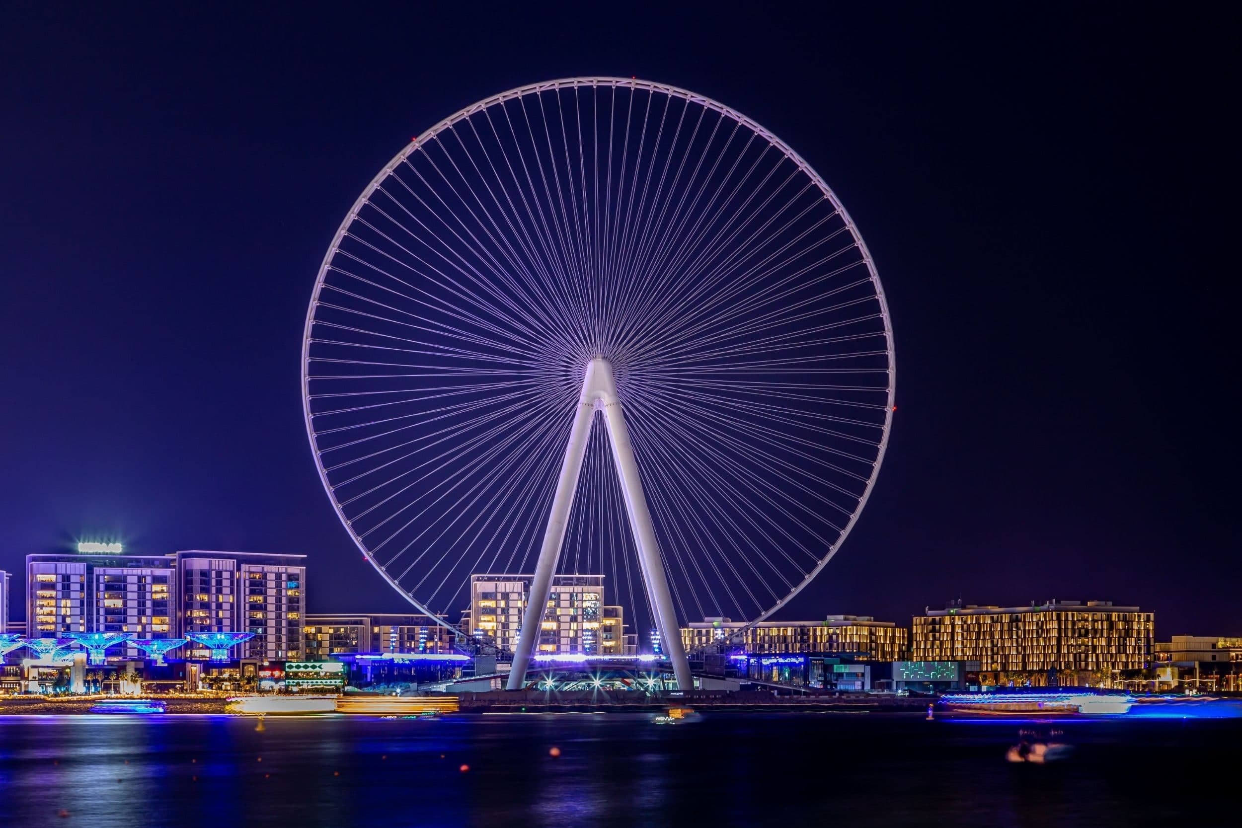 The Ain Dubai wheel lit up at night, with the Bluewaters residential buildings along the water below it