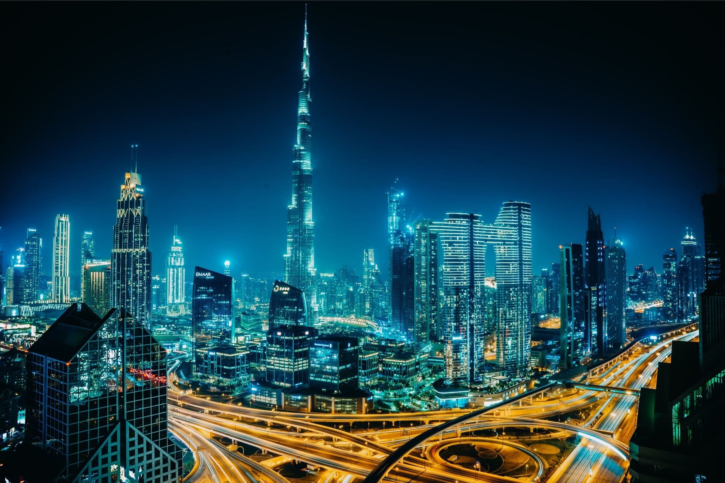 The Burj Khalifa and the towers of Downtown Dubai at night, with traffic on the roads below