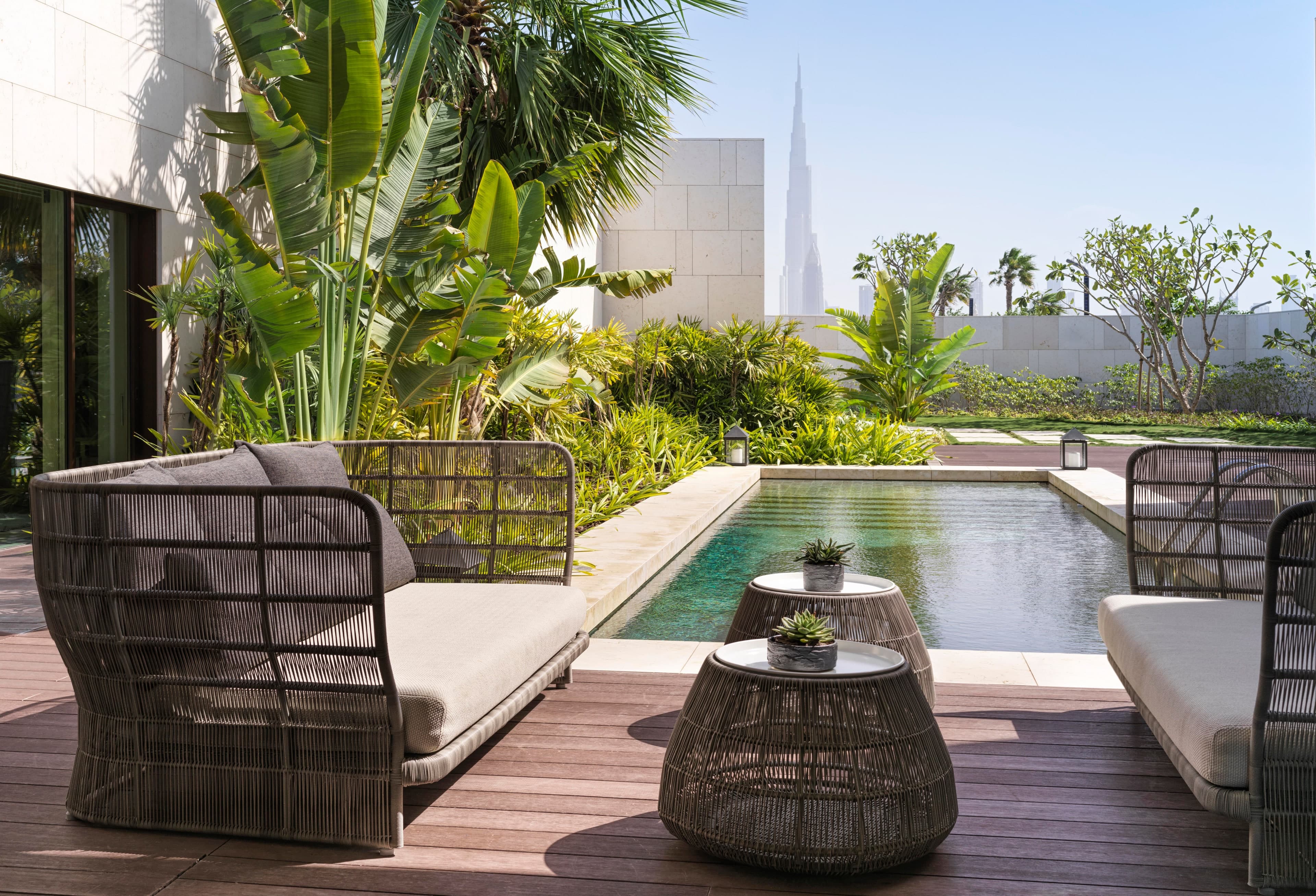 A private terrace with a plunge pool and garden at a Bulgari Resort villa on Jumeirah Bay Island, with the Burj Khalifa visible above the wall