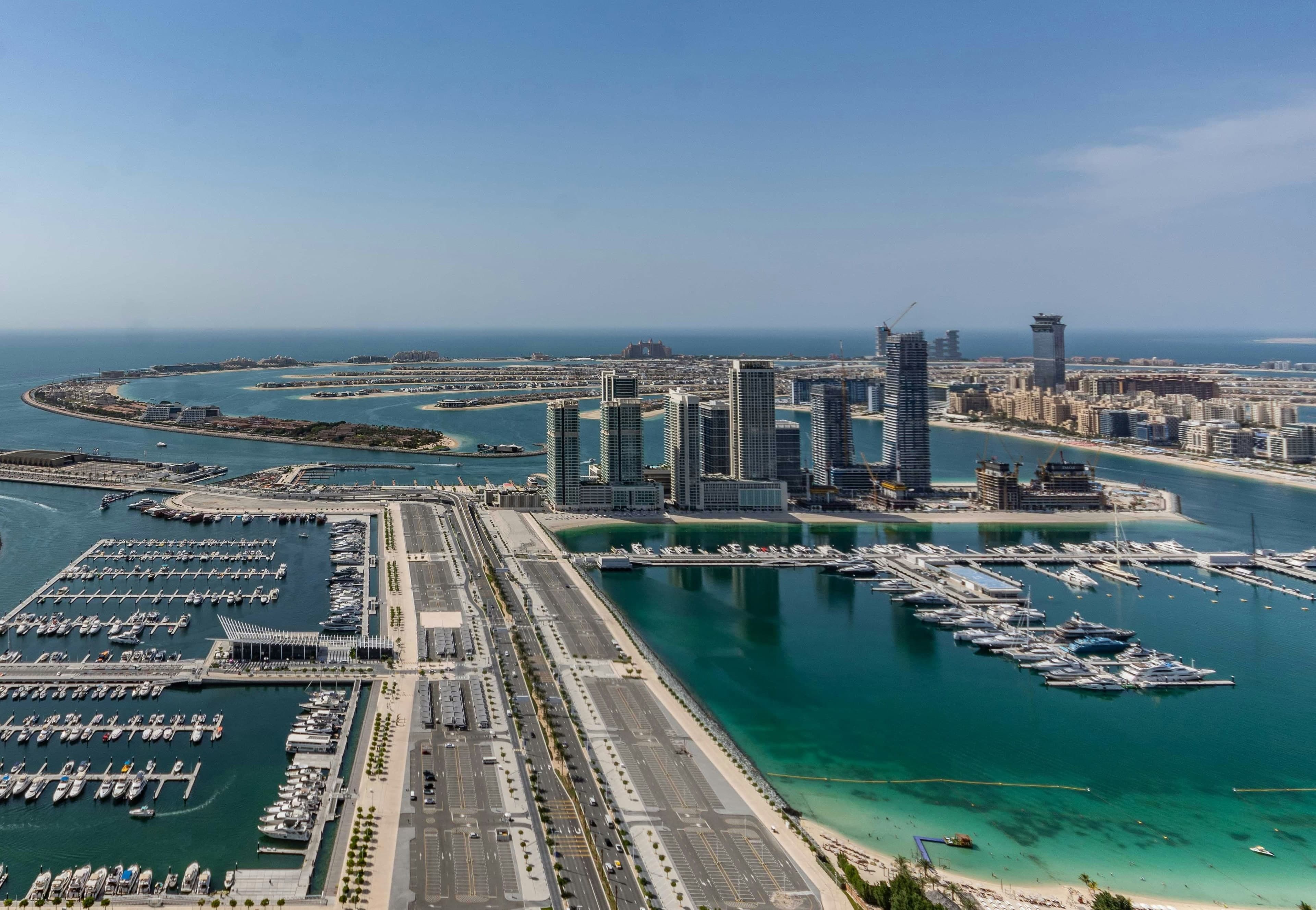 An aerial view of the Dubai Harbour marina and the towers of Emaar Beachfront on their peninsula, with Palm Jumeirah behind