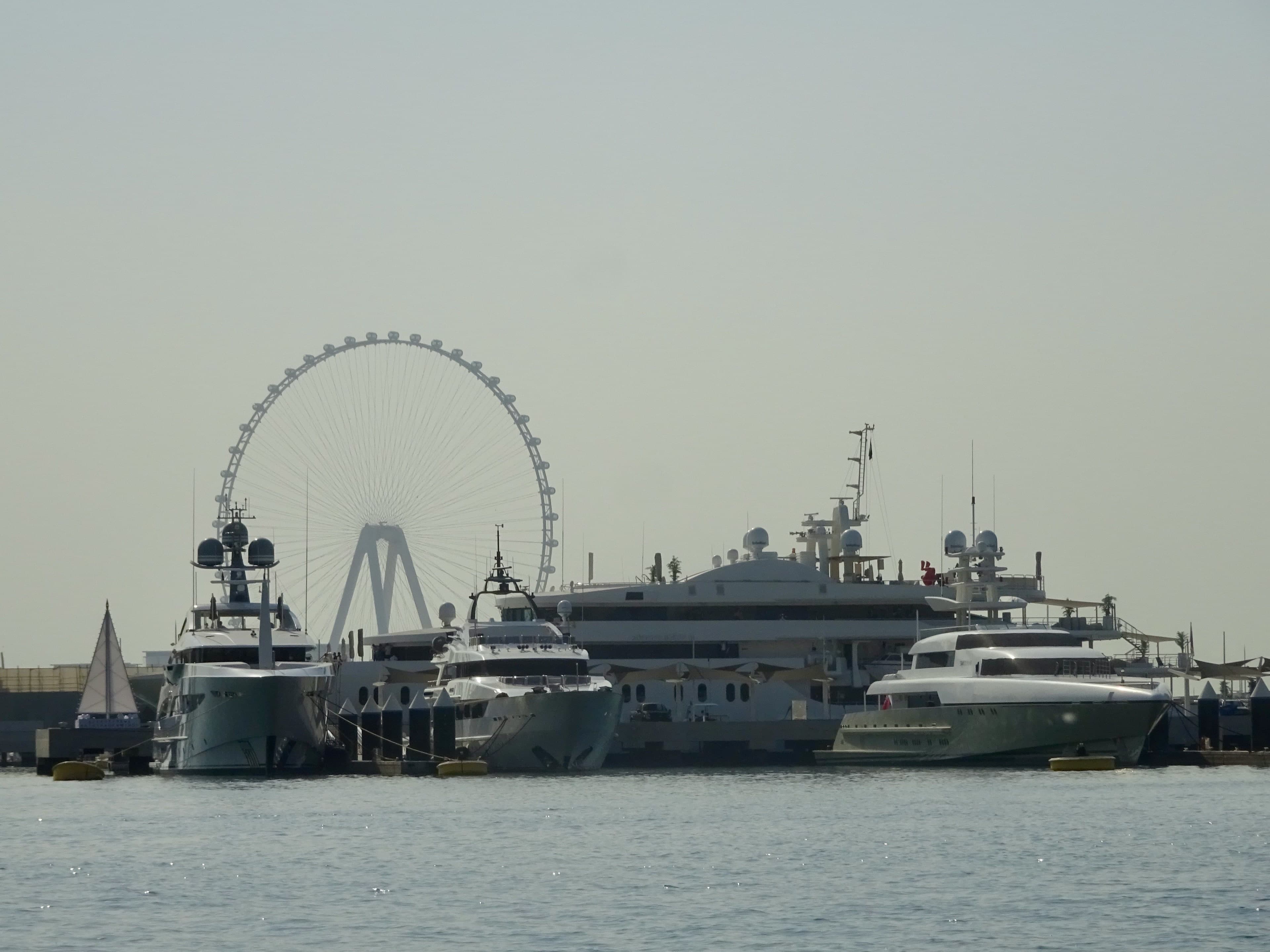 Superyachts moored at the Dubai Harbour marina, with the Ain Dubai wheel behind