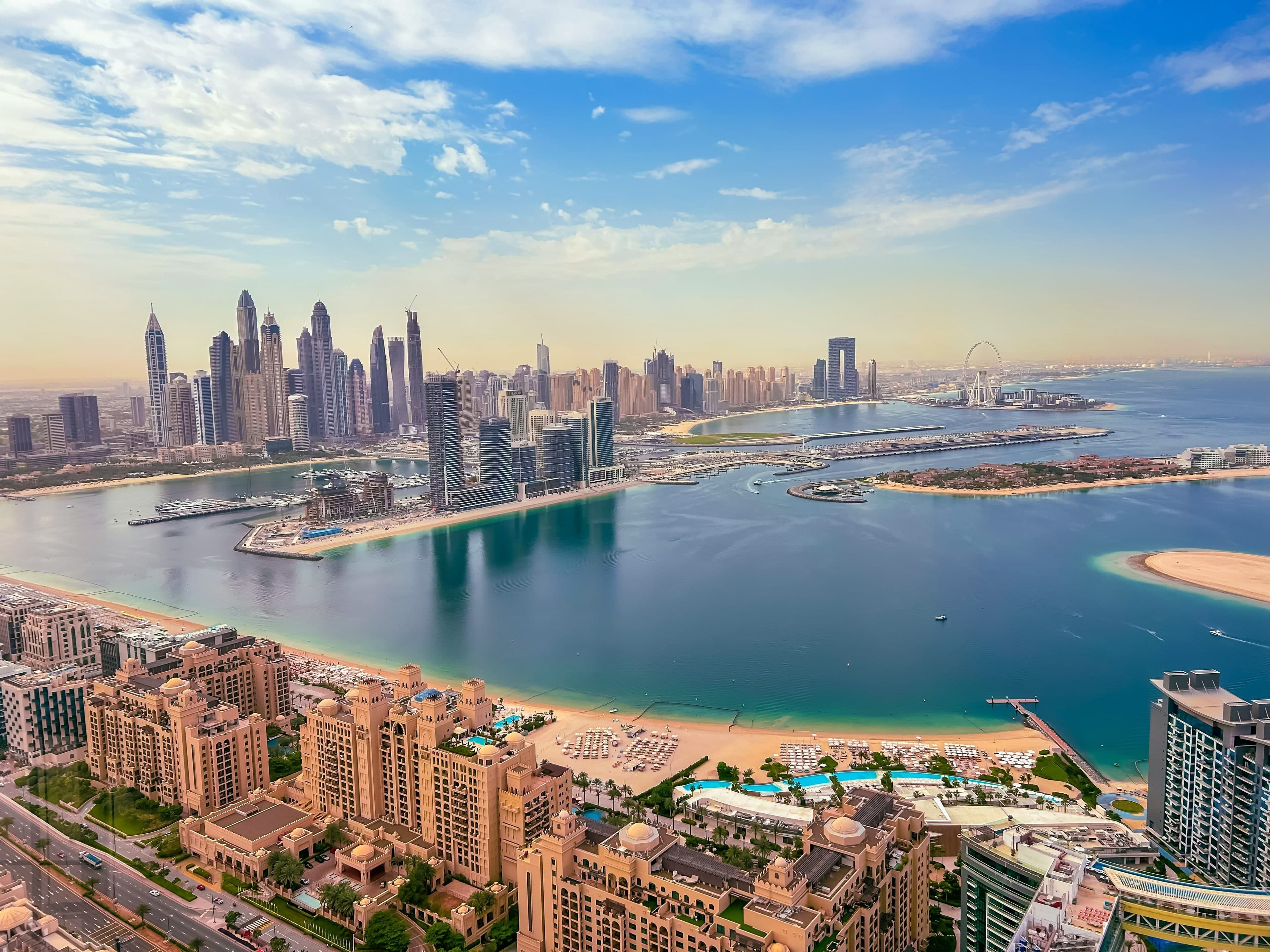 The towers of Emaar Beachfront and the Dubai Harbour marina seen from Palm Jumeirah, with the Dubai Marina skyline and the Ain Dubai wheel behind