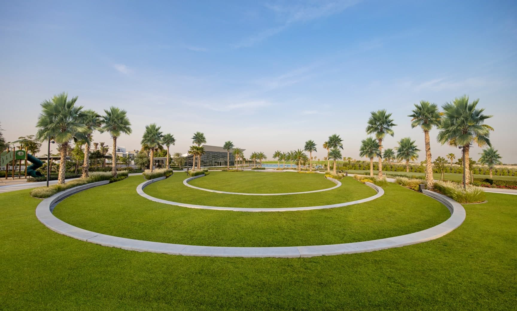 Circular lawns lined with palm trees in a park at Tilal Al Ghaf