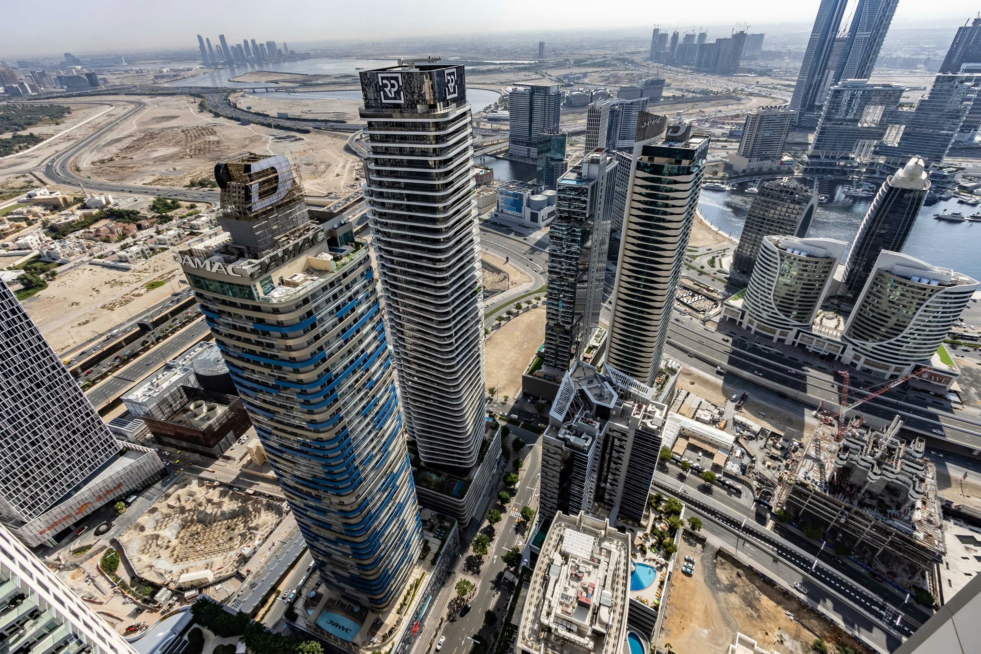 Residential towers in Business Bay seen from above, with streets and building sites below and the canal on the right