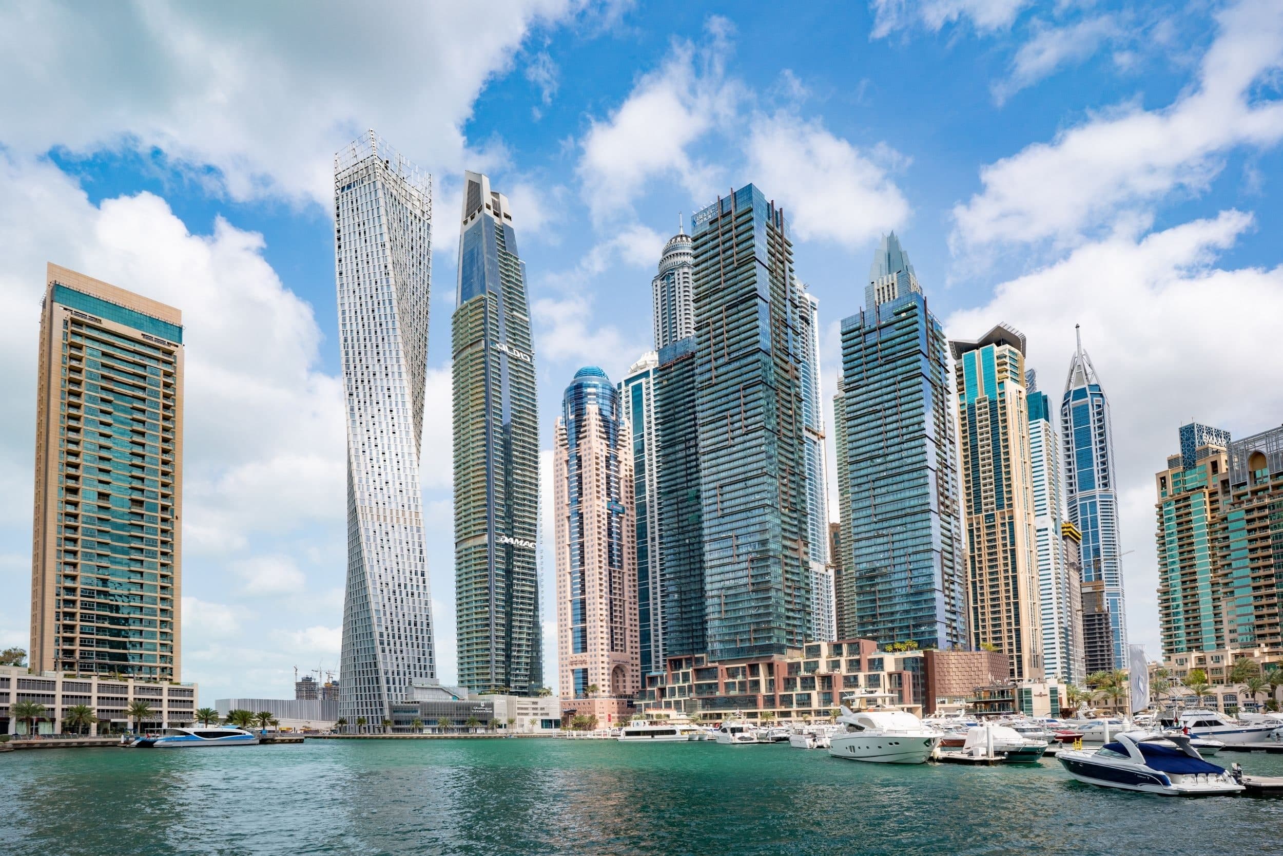 The twisting Cayan Tower and neighbouring towers in Dubai Marina, with motor yachts moored at the water's edge